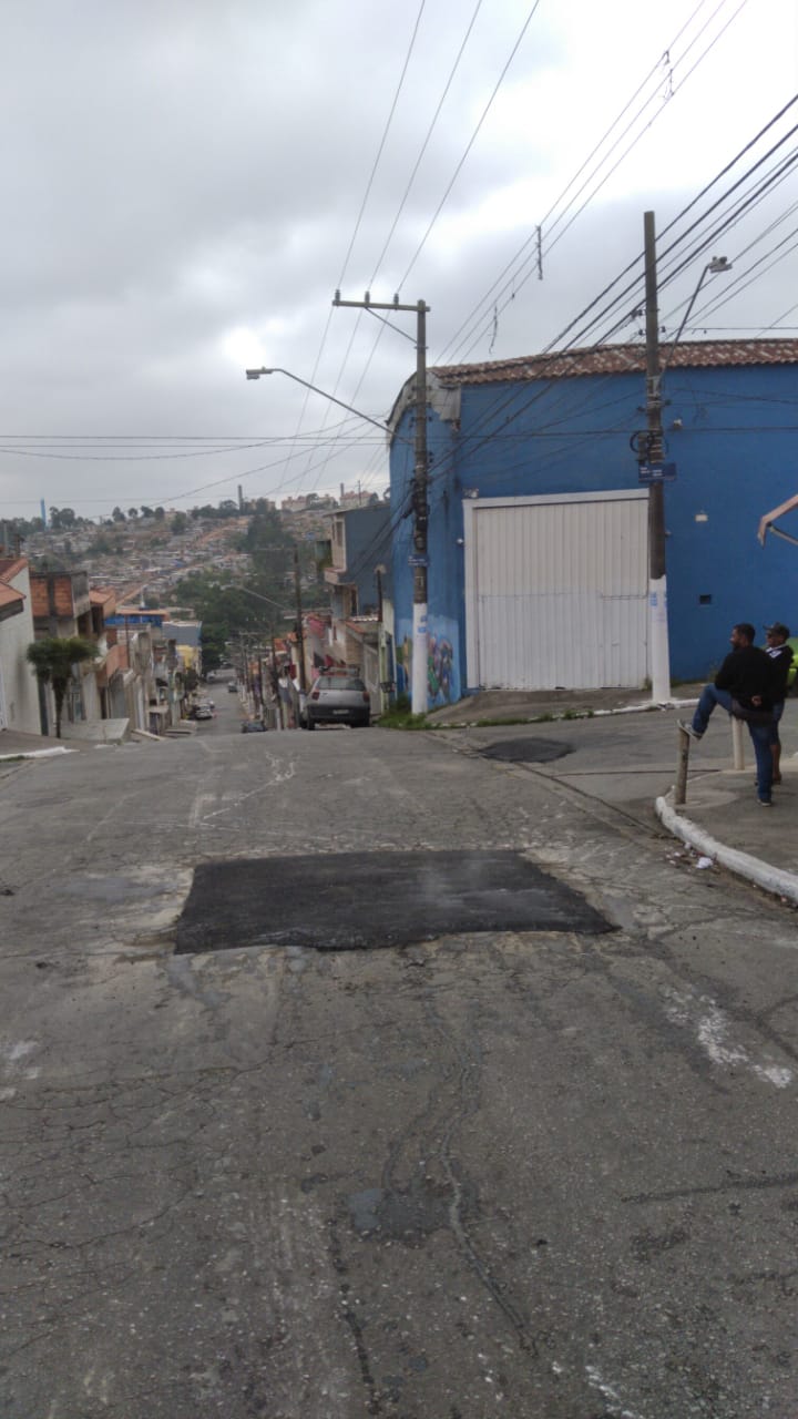 local do buraco tapado é notável, com mancha retangular preta, no meio da pista